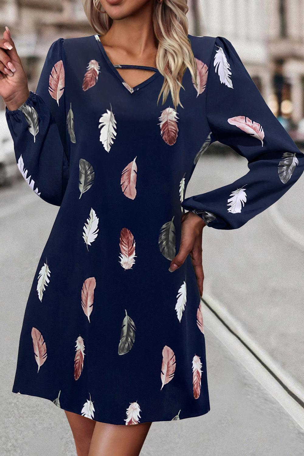 Navy feather print mini dress with cutout neckline and long sleeves.