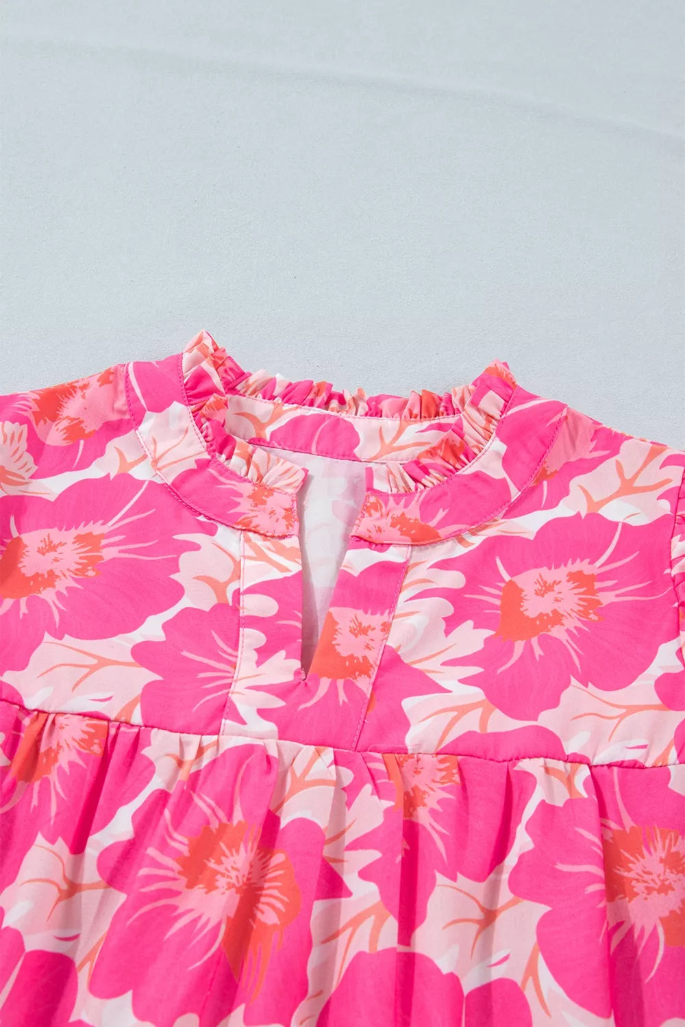 Vibrant floral print polyester blouse with ruffled V-neck and bubble sleeves.