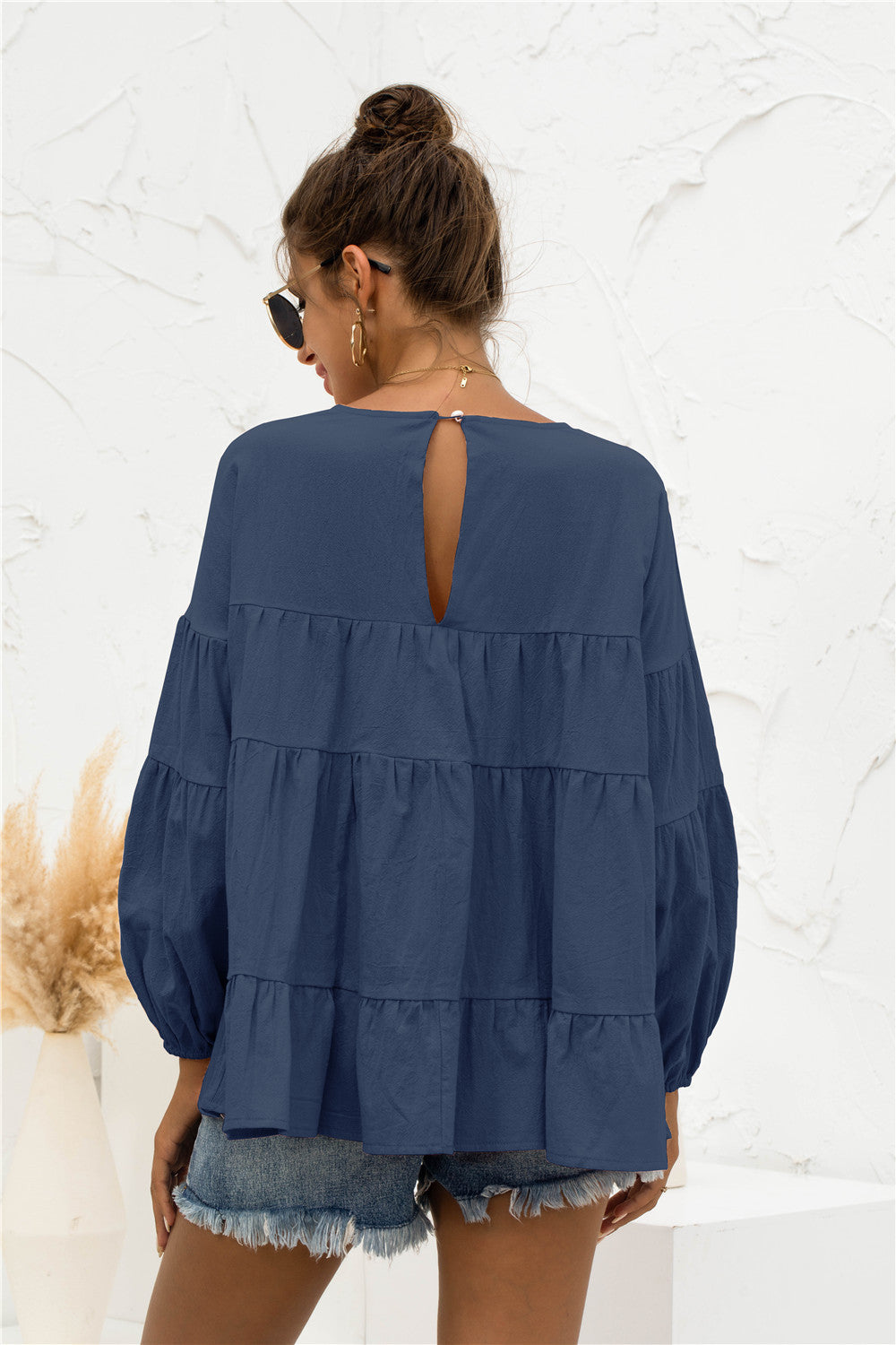 Navy tiered peasant blouse with ruffled bubble sleeves and keyhole back detail.