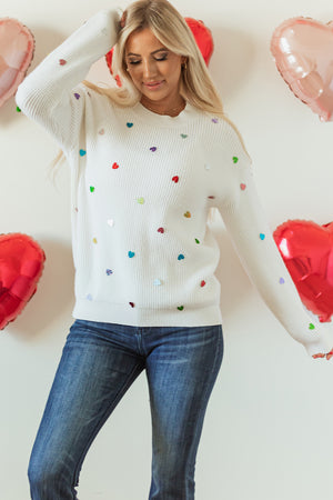 White ribbed knit sweater with colorful heart embellishments, crew neck, long sleeves.