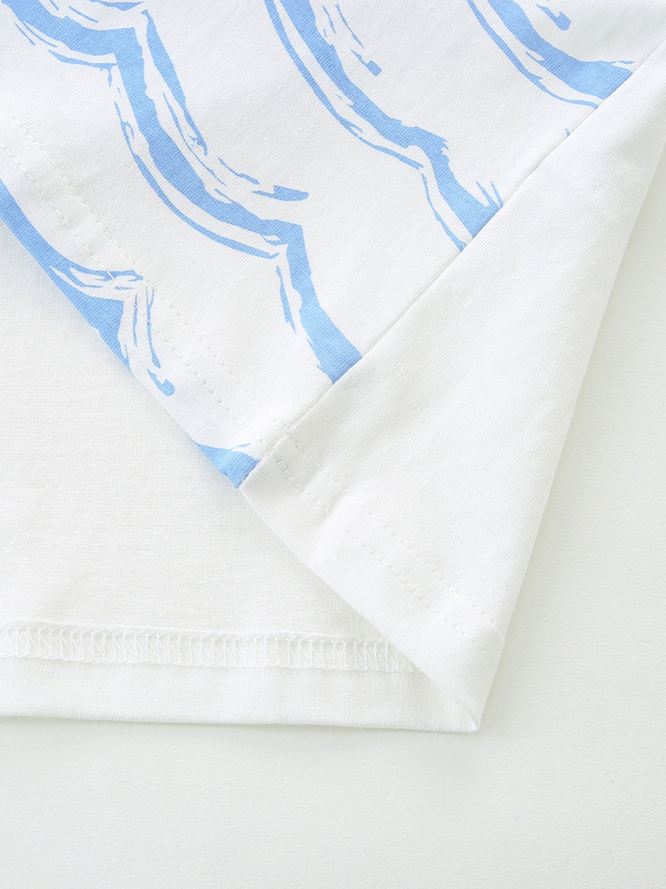 White cotton toddler t-shirt with blue abstract wave print and stitched hem.
