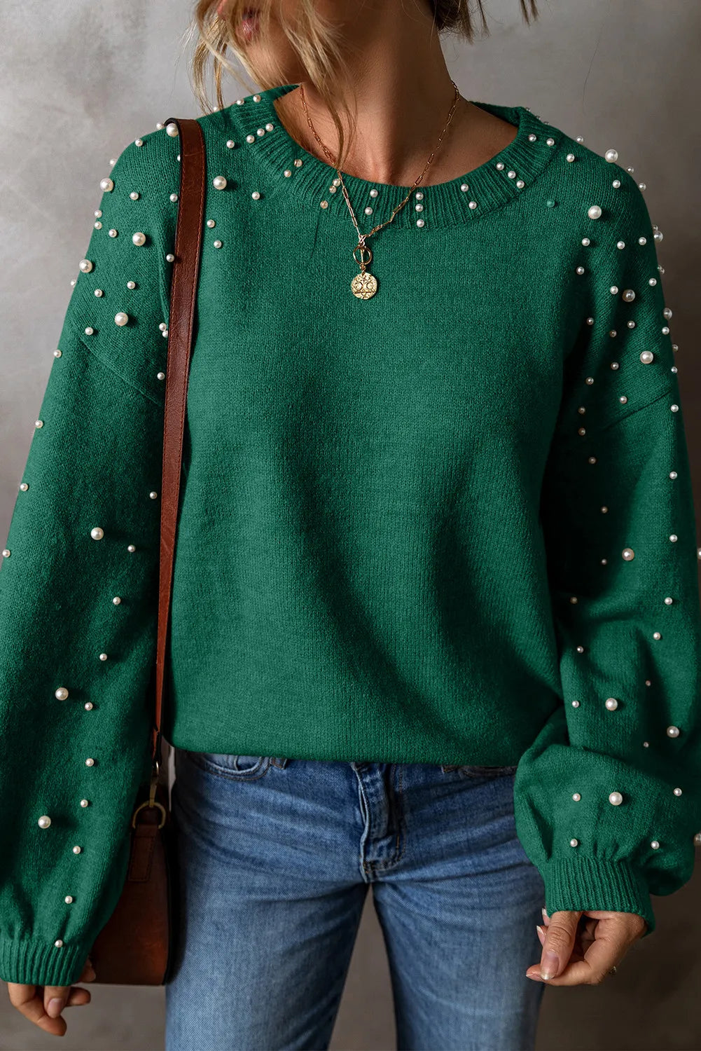 Dark green knit sweater with pearl embellishments on the neckline and sleeves.