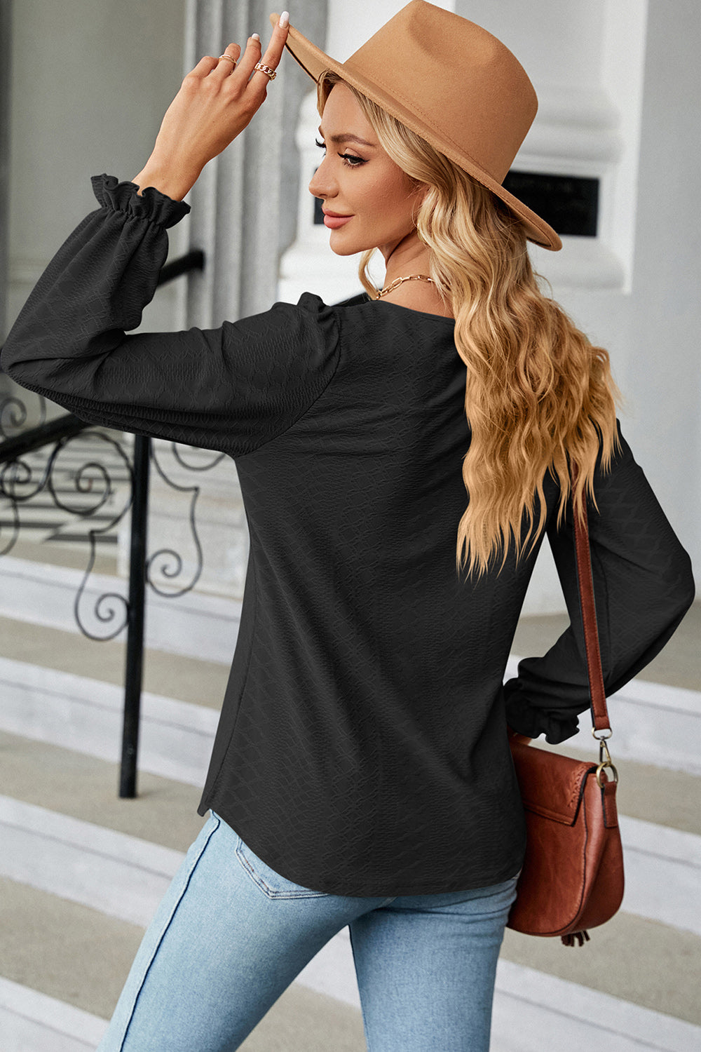 Black textured puff sleeve blouse with ruffled cuffs and a square neckline.