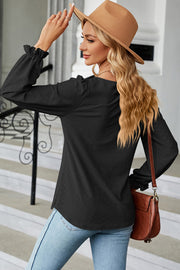 Black textured puff sleeve blouse with ruffled cuffs and a square neckline.
