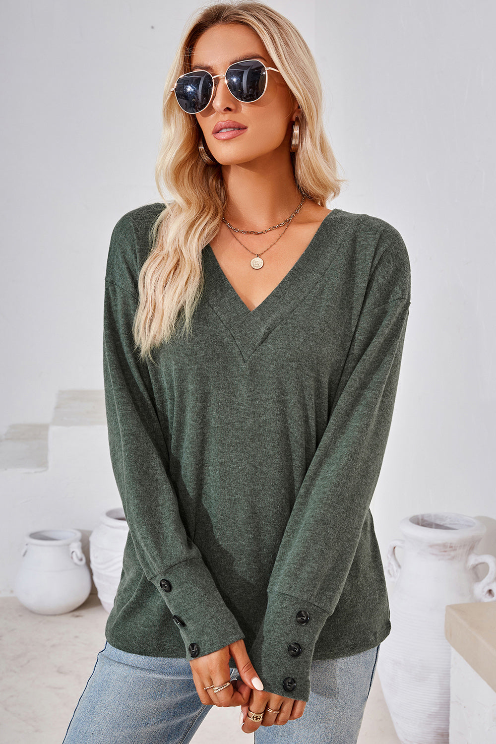 Button-cuff slouch v-neck top in dark green with button details on sleeves.