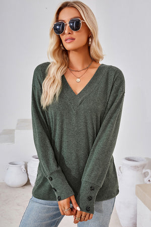 Button-cuff slouch v-neck top in dark green with button details on sleeves.