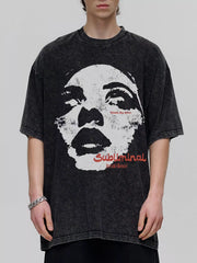 Oversized dark gray graphic tee with a distressed wash and a large black and white face print with red text.