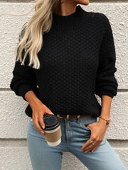 Black textured mock-neck sweater with long sleeves, styled casually with jeans and a coffee cup.