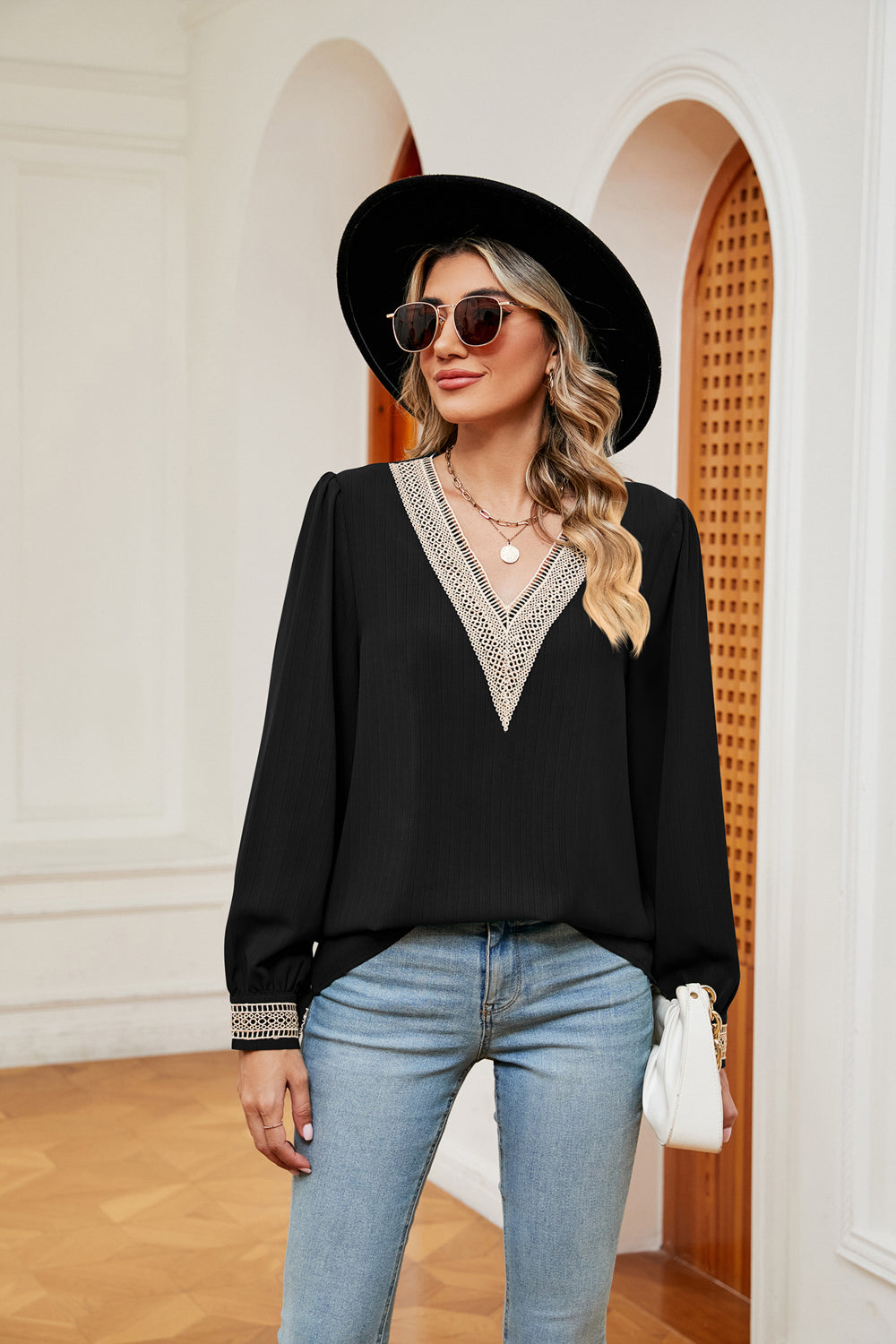 Black blouson top with V-neck embroidered trim and cuff detail.