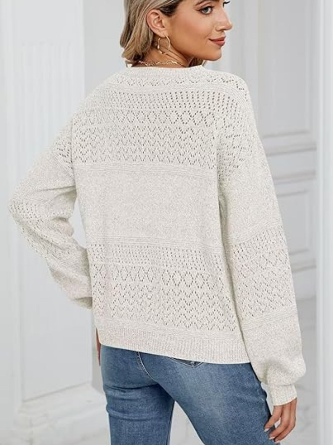 White eyelet stitch V-neck pullover sweater with textured knit details and long sleeves.
