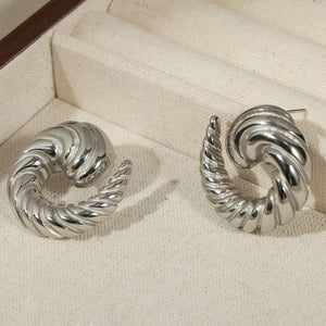 Silver sculptural swirl stud earrings with a twisted, textured design.