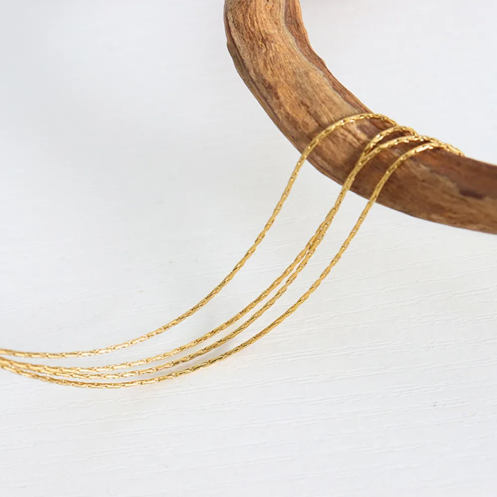 Delicate multi-strand gold-plated chain necklace with a textured pattern.