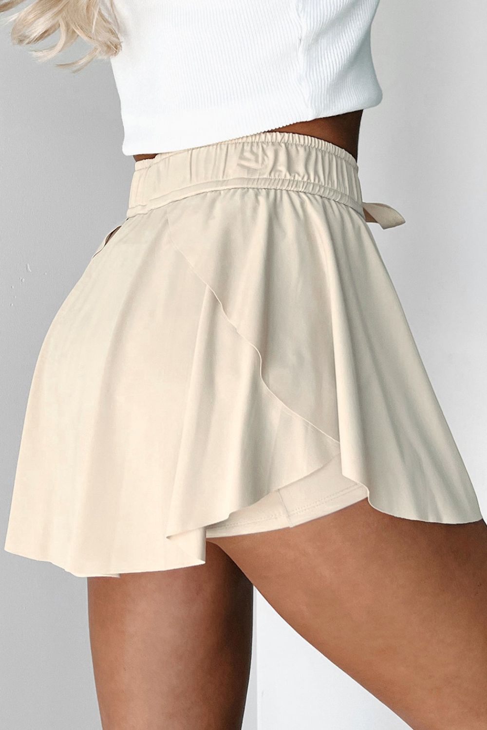 Beige ruffled skort with tie waist detail and elastic waistband.