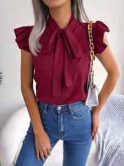 Burgundy ruffled sleeve pussybow blouse with a tie neck, styled with jeans.