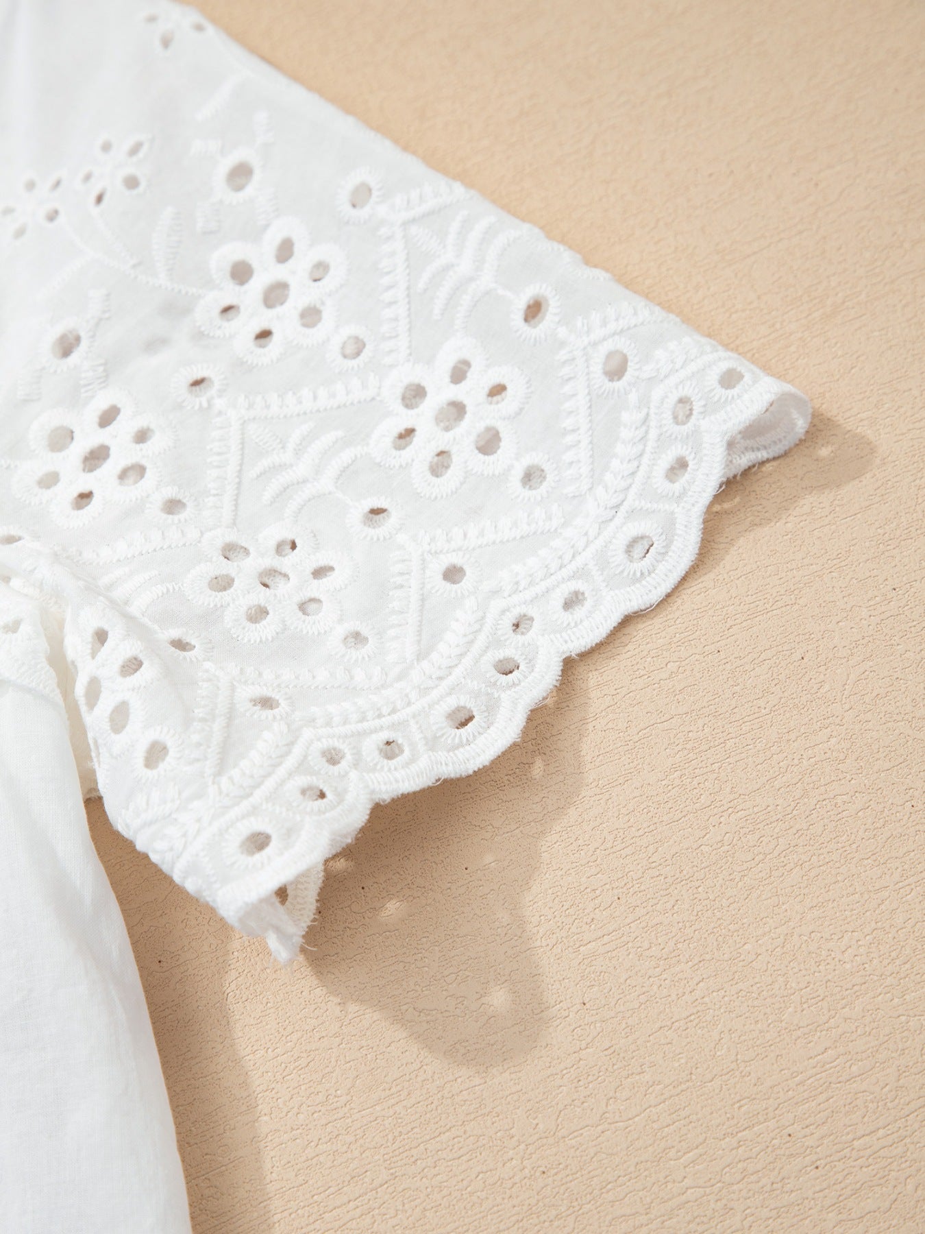 White cotton eyelet embroidered sheer shirt with floral detail and scalloped hem.