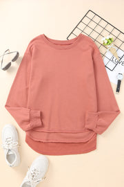 Rose pink sweatshirt with asymmetric hemline and raw edge detail.