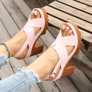 Pink open toe block heel sandals with cross straps and a chunky sole.