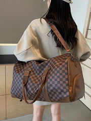 Chic checkered travel bag with brown leather accents and adjustable strap.