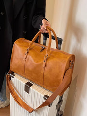 Cognac vintage leather duffle bag with top handles and crossbody strap on luggage.