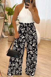 Black botanical ruffle waist palazzo trousers with a white halter top.