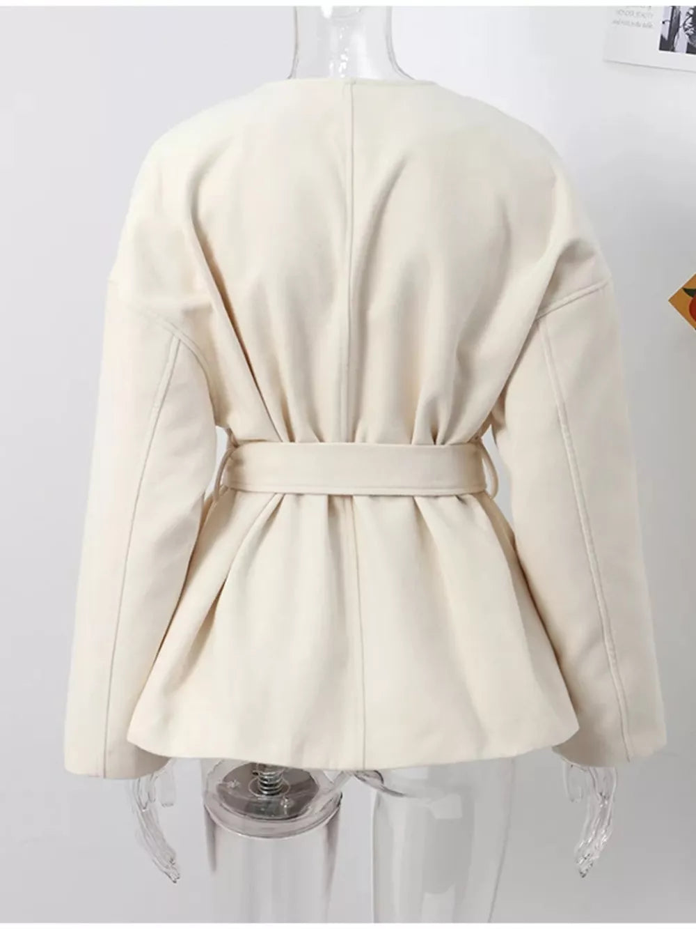 Beige belted trench coat with dropped shoulders and tie waist detail.