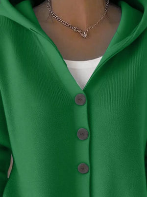 Green knit cardigan with button front and hood, layered over a white top.