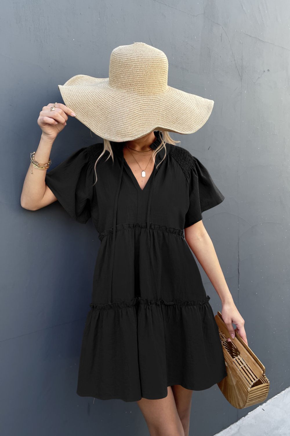 Black tiered ruffle sleeve trapeze dress with V-neck and tie detail.