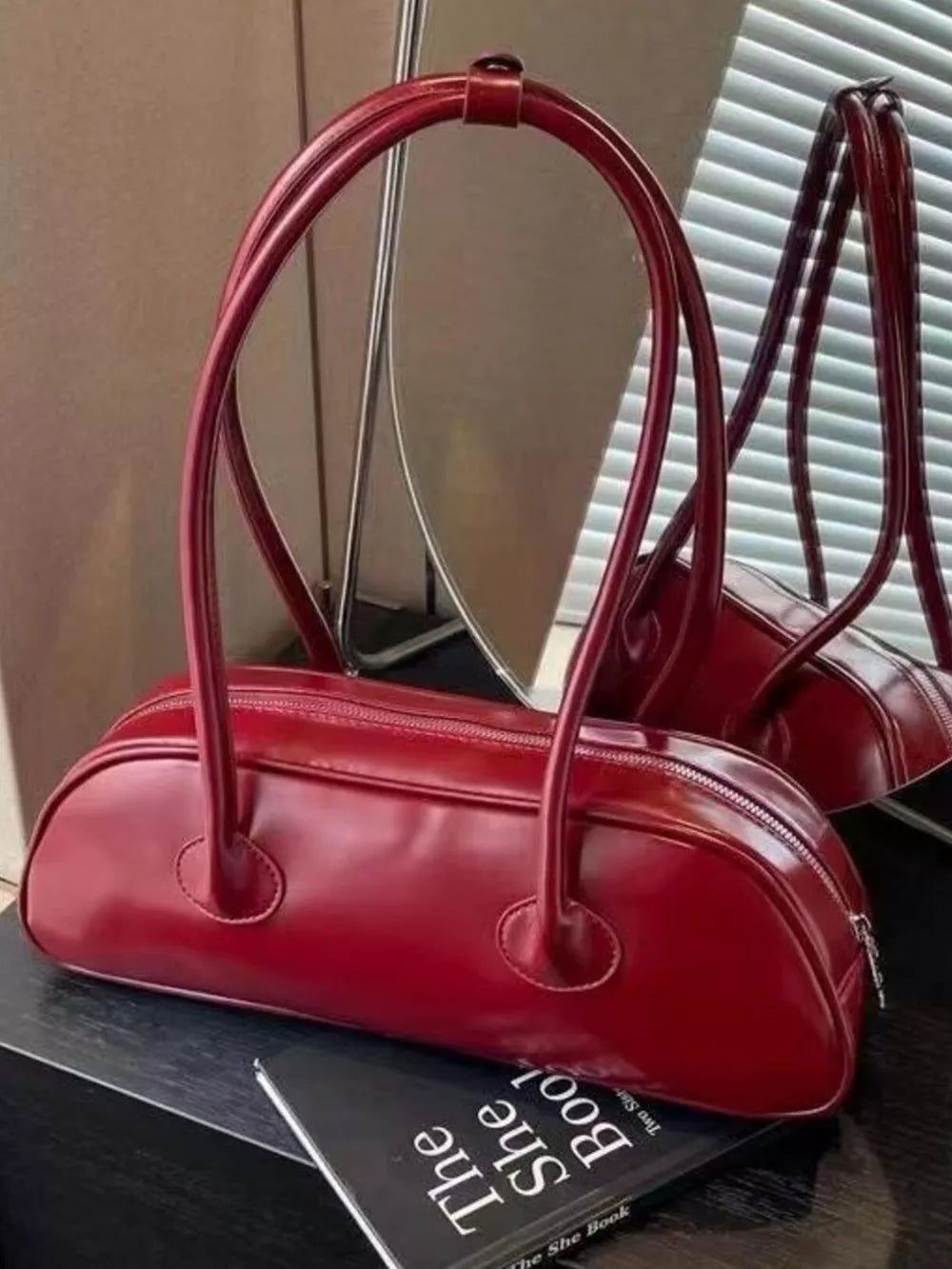 Chic red barrel shoulder bag with double top handles and a zip closure.