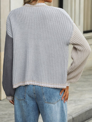 Colorblock acrylic knit cardigan with ribbed trim and balloon sleeves, in gray and beige tones.