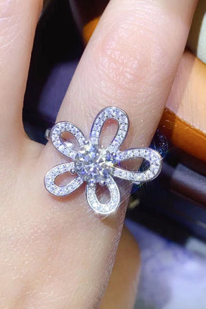 White moissanite flower ring with pavé details on a finger
