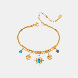 Gold celestial charm bracelet with turquoise accents, featuring sun and tree charms.
