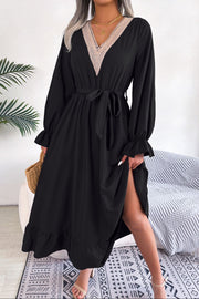 Black midi dress with lace trim V-neck, tie waist, ruffled cuffs and hem, and a thigh-high slit.