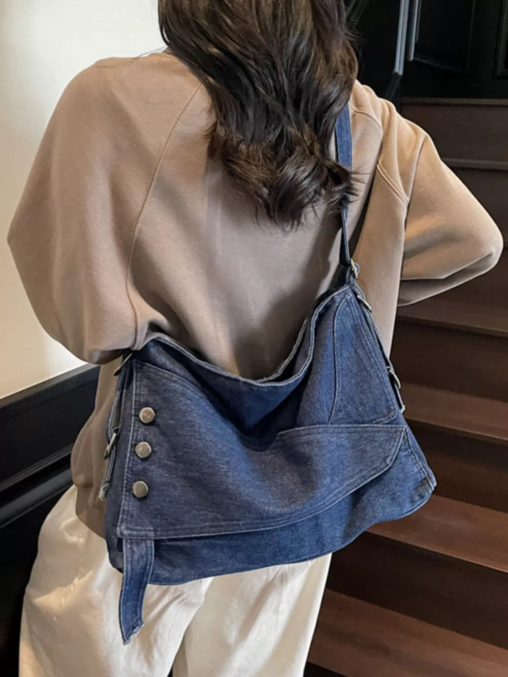 Relaxed denim crossbody bag with button accents and adjustable strap.