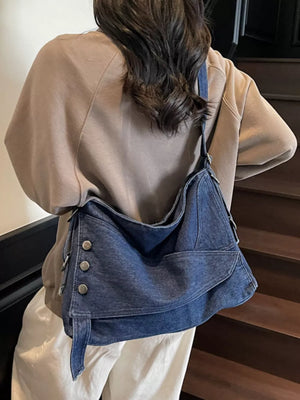 Relaxed denim crossbody bag with button accents and adjustable strap.