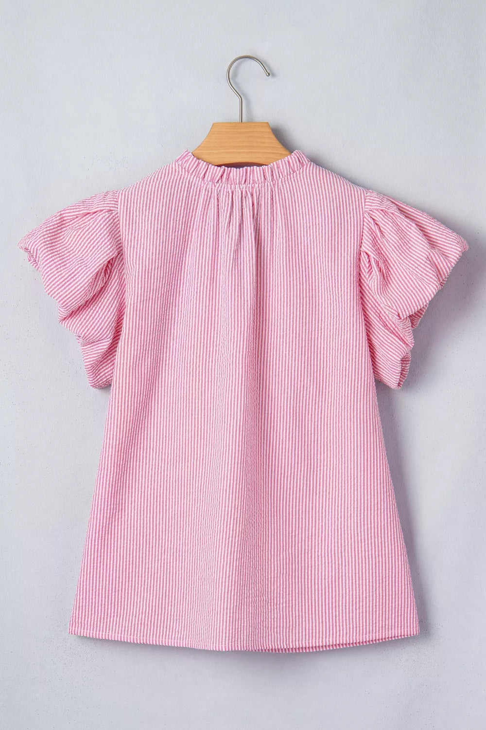 Pink and white striped textured short sleeve blouse with ruffled neckline and puff sleeves.
