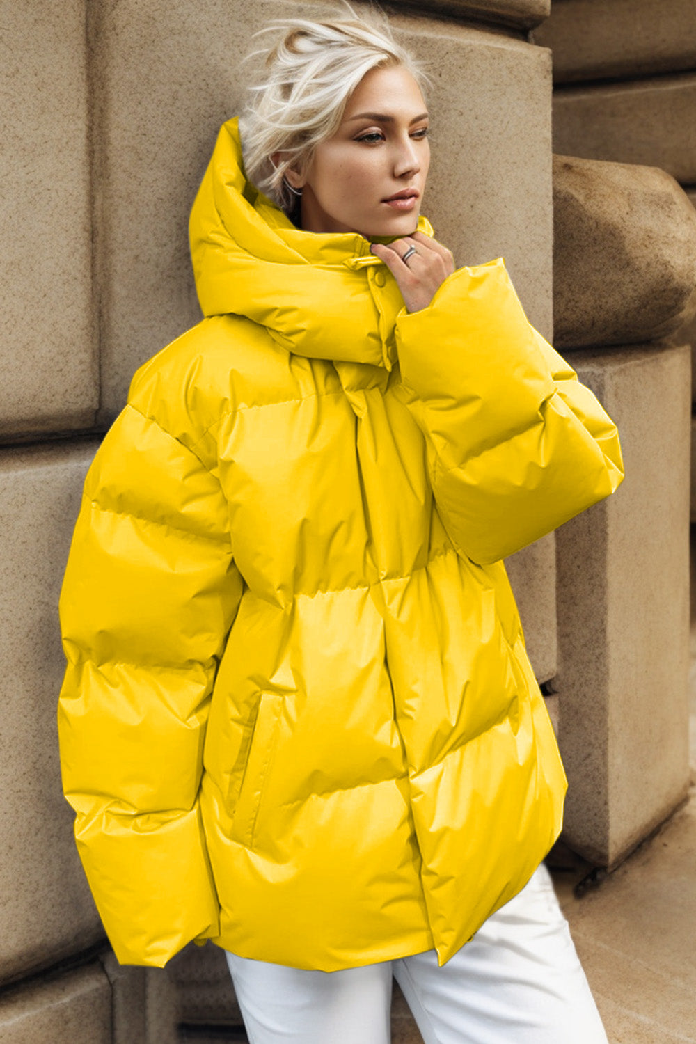 Yellow oversized puffer jacket with hood and cinched waist detail.