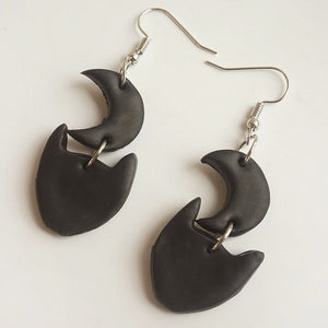 Black Halloween charm drop earrings featuring crescent moon and cat face charms.