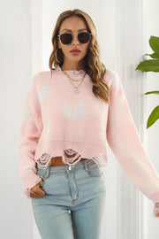 Pink acrylic cropped sweater with butterfly intarsia and frayed hem detail.
