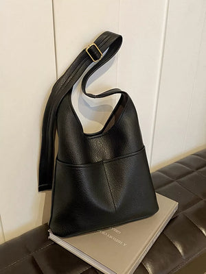 Black textured PU leather shoulder bag with adjustable strap and front pocket detail.