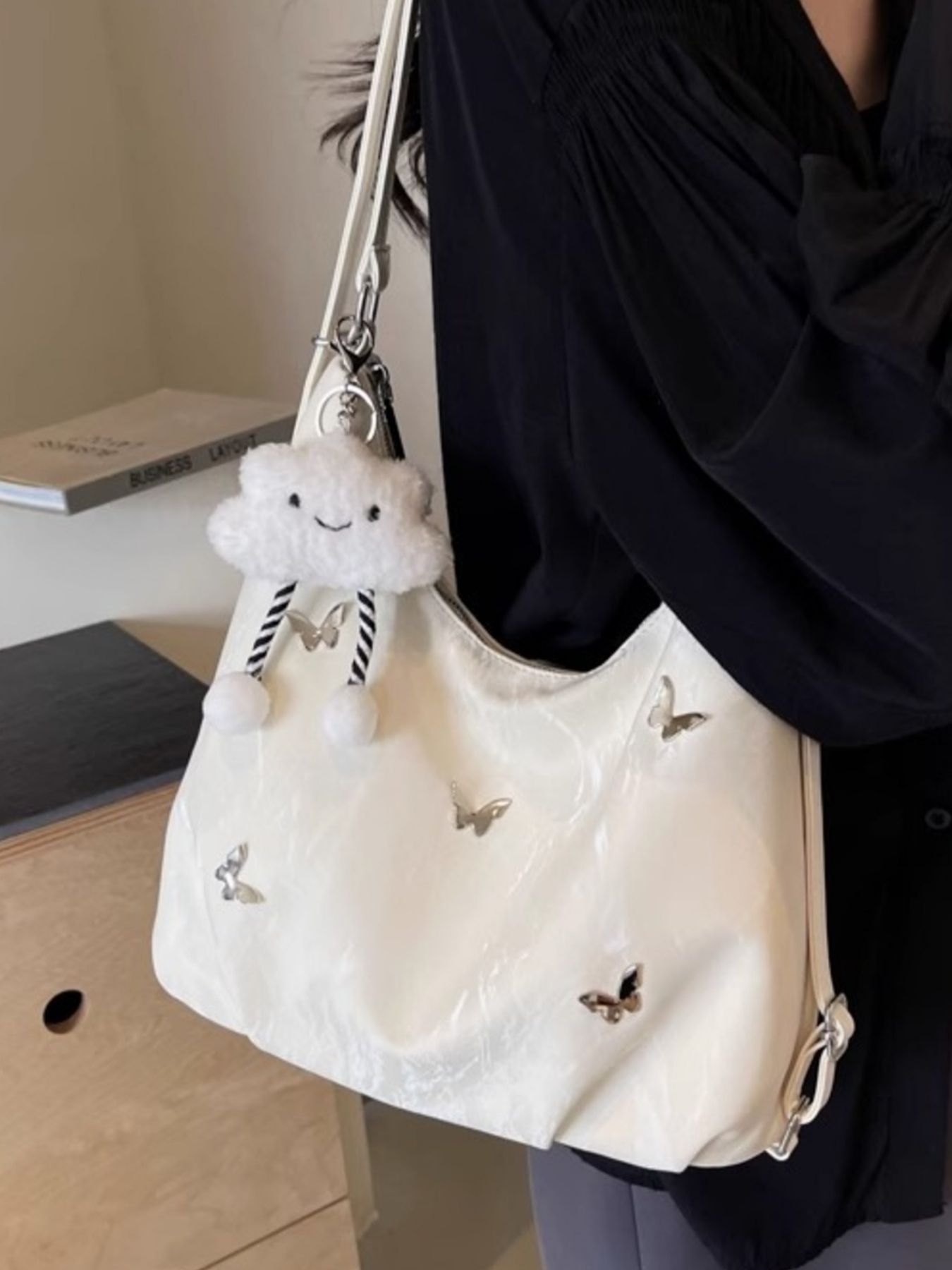 White shoulder bag with butterfly appliques and a cloud charm.