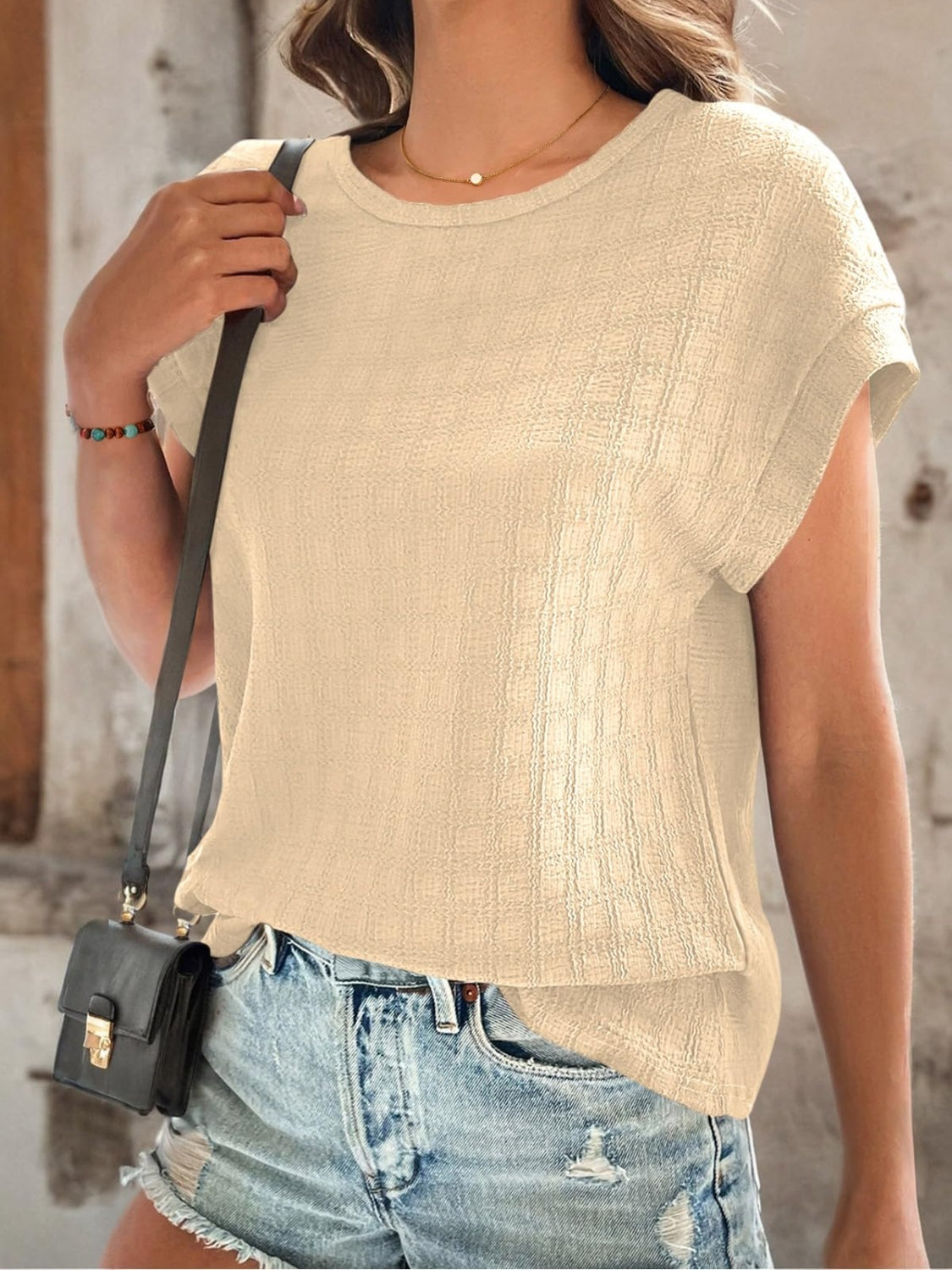Tan woven texture cap-sleeve top with a crew neck, styled with denim shorts.
