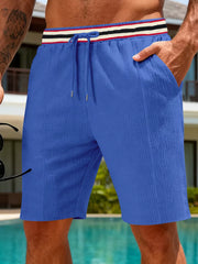 Blue textured drawstring shorts with a striped waistband and pockets.