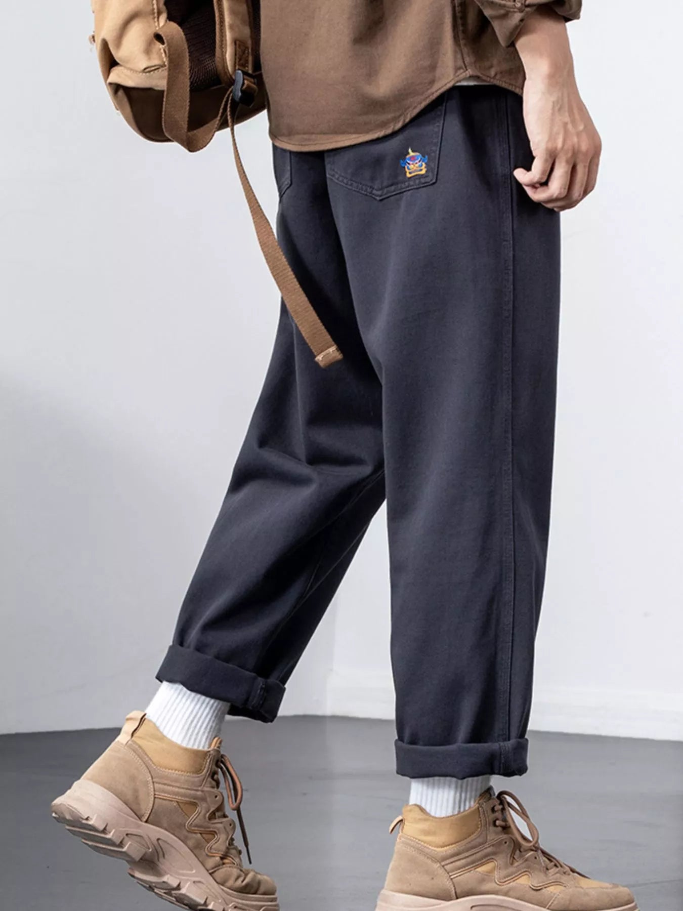 Plus-size dark gray cotton wide-leg trousers with cuffed hems and embroidered back pocket detail.