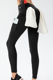 Black athletic leggings with phone pocket and utility pockets, towel draped on hip.