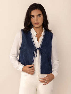 Dark blue suede-effect vest with white stitch trim and tie front, worn over a white shirt.
