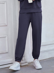 Dark blue cuffed joggers with a relaxed fit, styled with white sneakers.