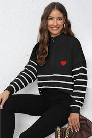 Black zip knit sweater with white stripes and red heart patch detail.