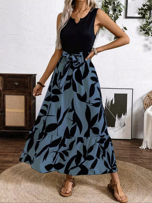 Maxi dress with black leaf print on blue-grey, V-neck, sleeveless, belted waist, tiered hem