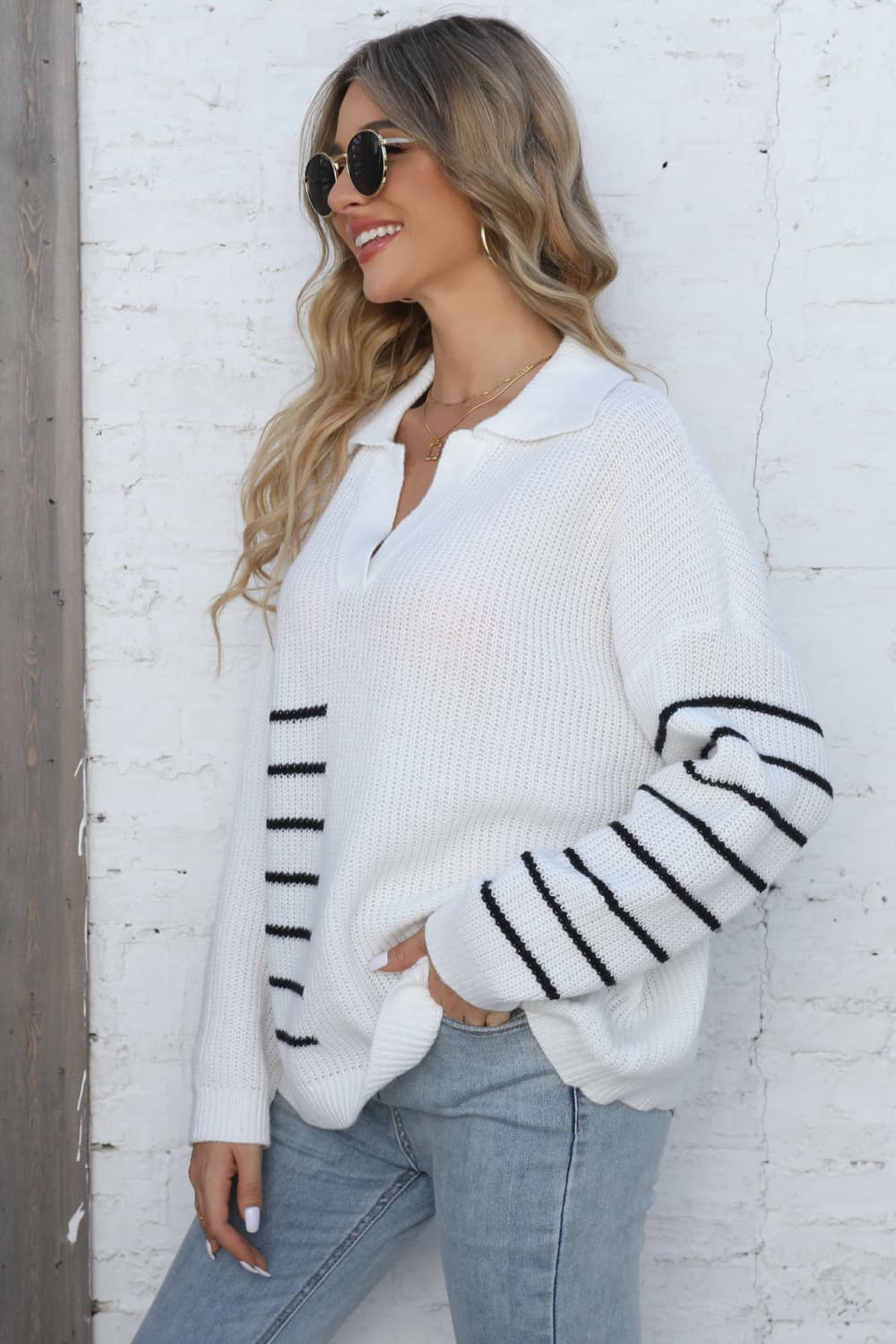 White collared knit sweater with black stripe block detail on sleeves and chest.