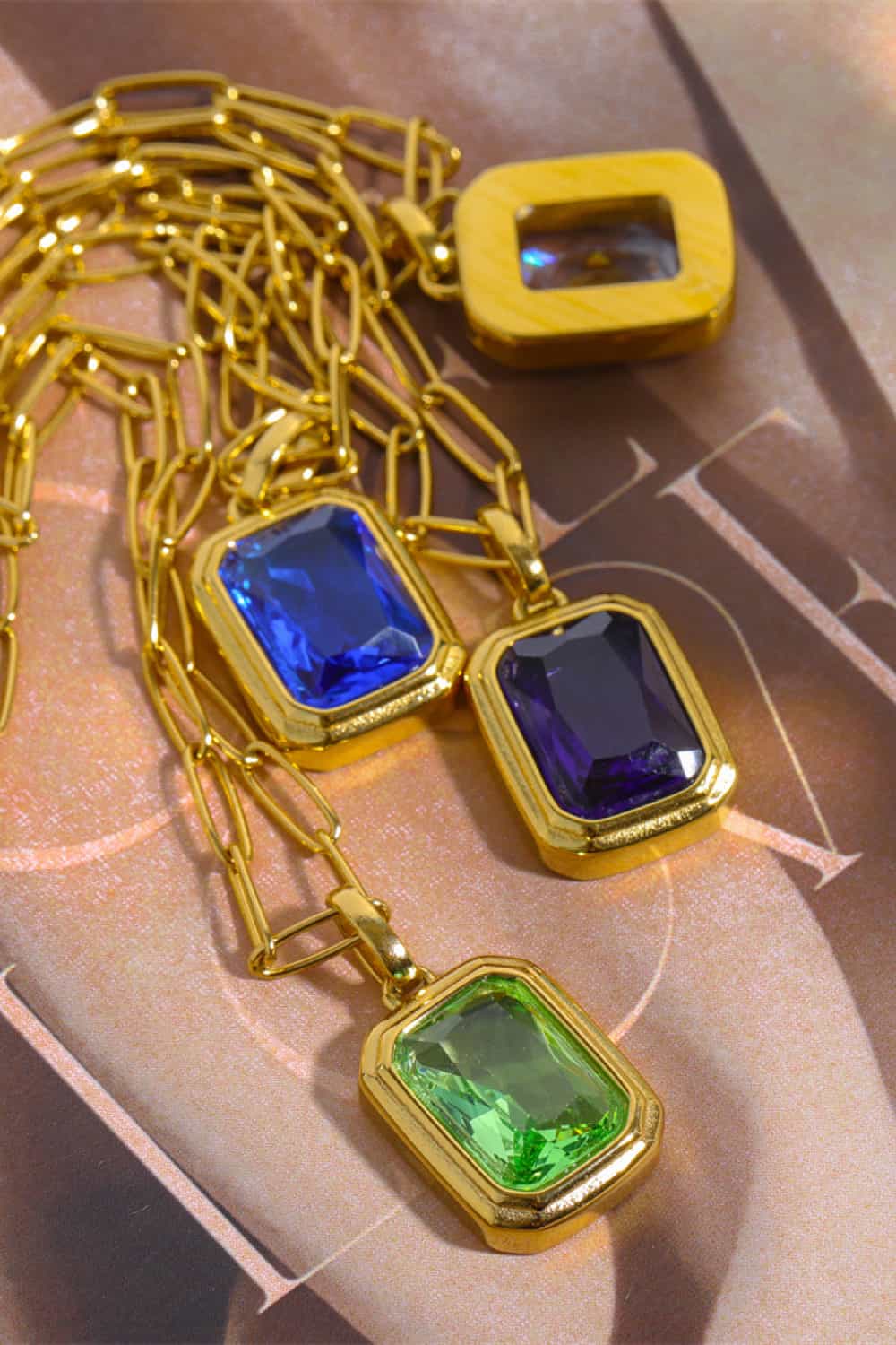 Gold chain necklace with royal blue, purple, and light green rectangular gemstone pendants.